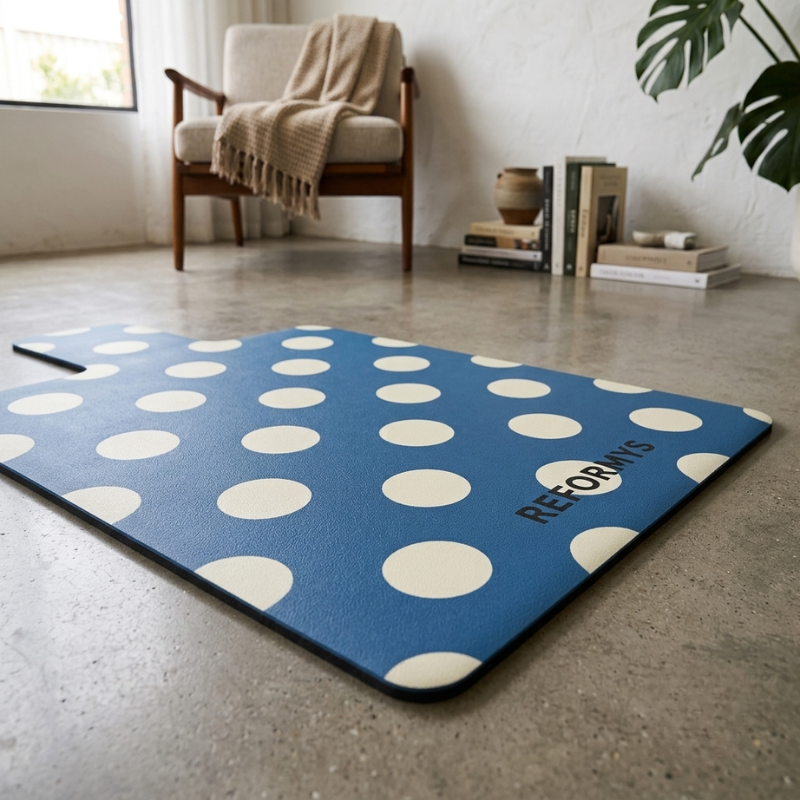 Close-up of the Reformys Pilates Reformer Mat in Ocean Dot laid on concrete flooring of a home lounge