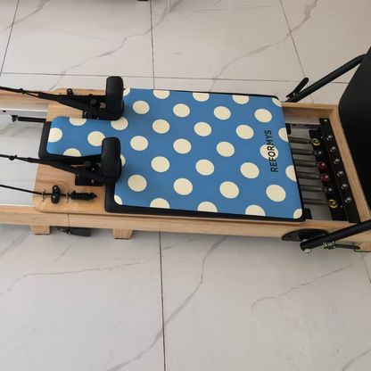 Top view of the Reformys Pilates Reformer Mat in Ocean Dot on a Pilates reformer machine inside a marble floor studio