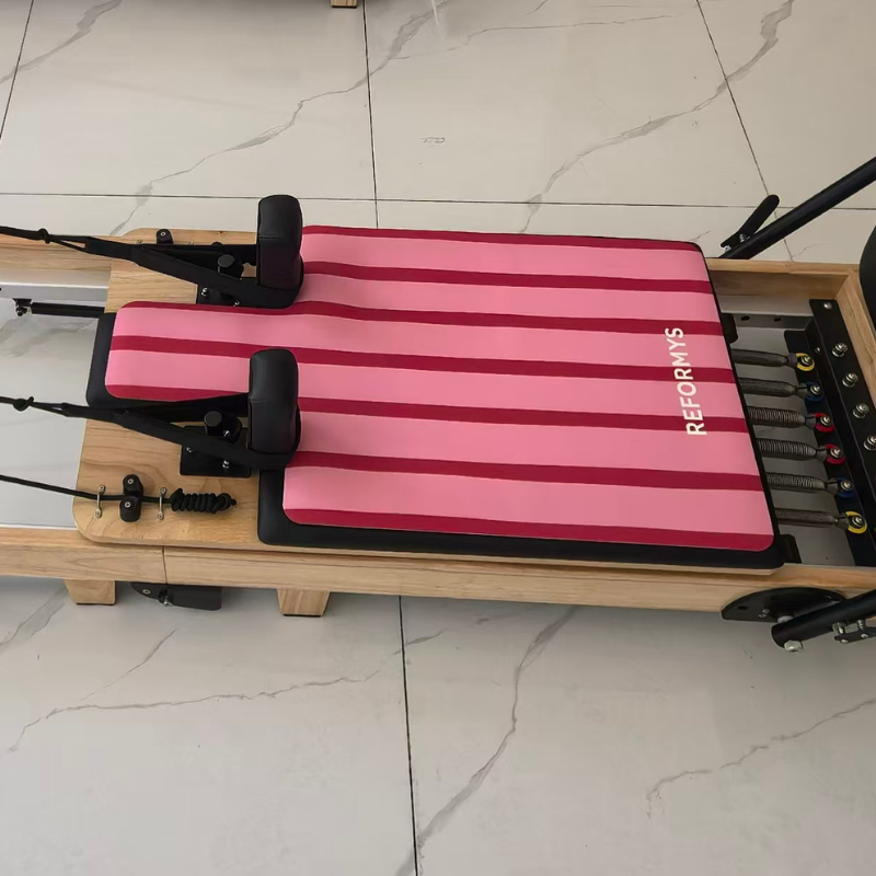 Reformys Pilates Reformer Mat in Sweet Rebel on a Pilates reformer inside a marble floor studio